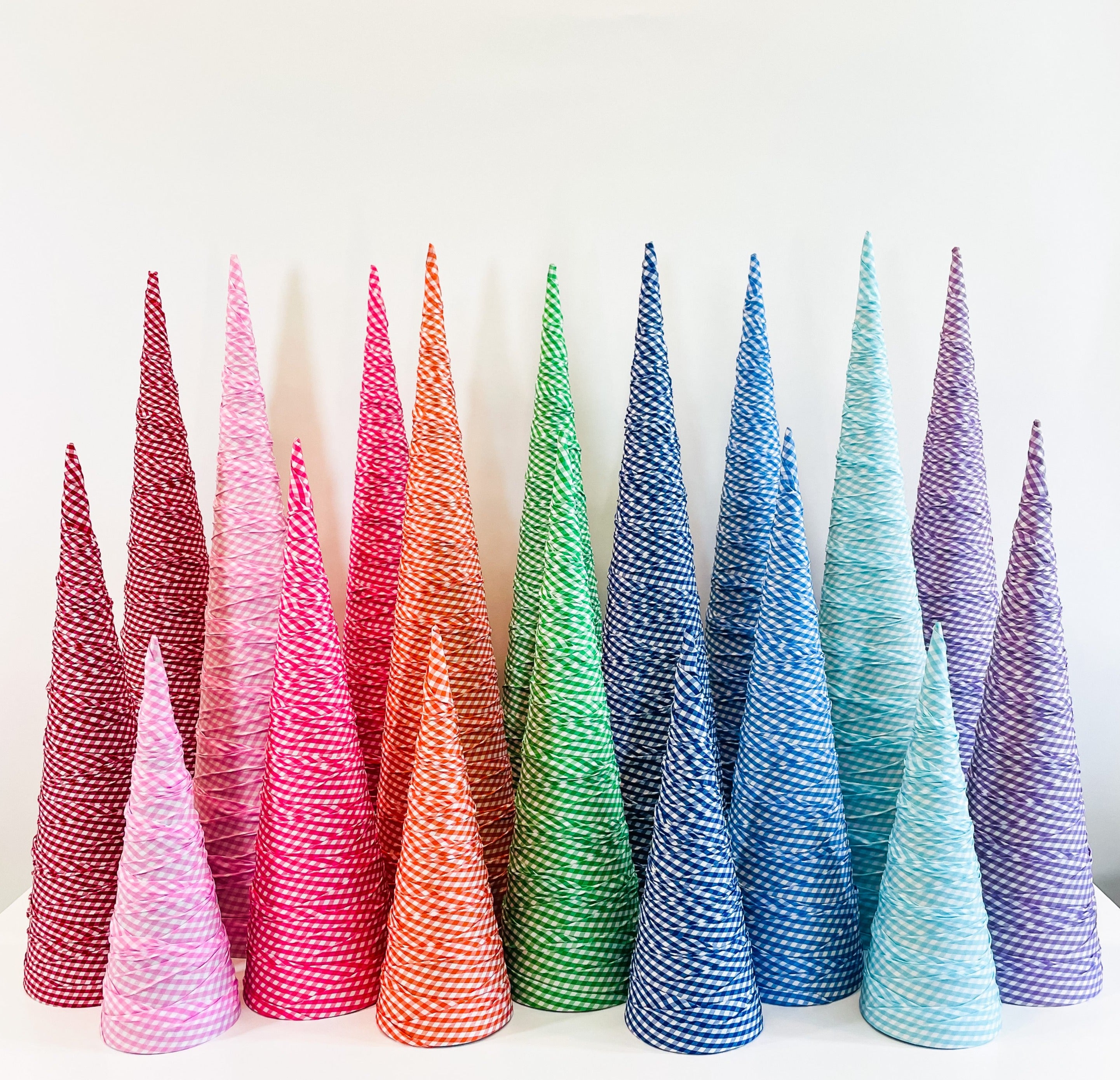 A collection of gingham fabric-wrapped paper mache cones designed to resemble Christmas trees, arranged in a row with a variety of colors.